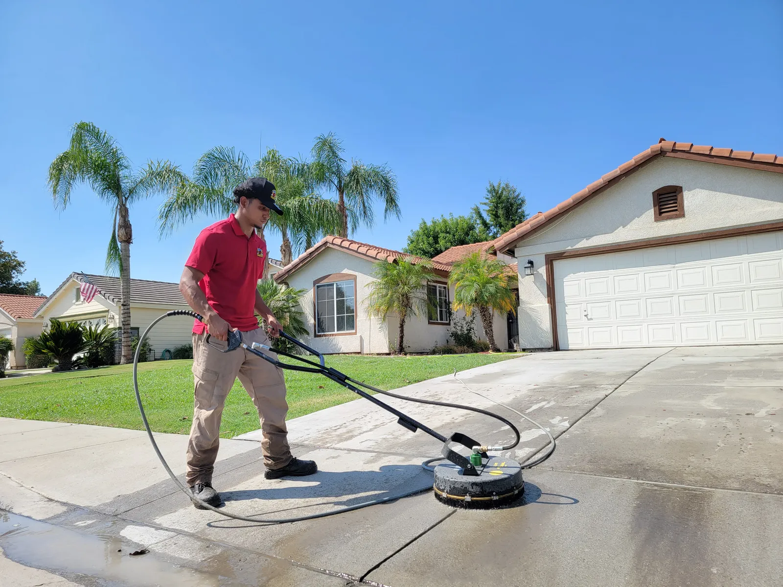 Concrete driveway cleaning in Bakersfield, CA — power washing a residential driveway in front of a tile-roof Bakersfield home